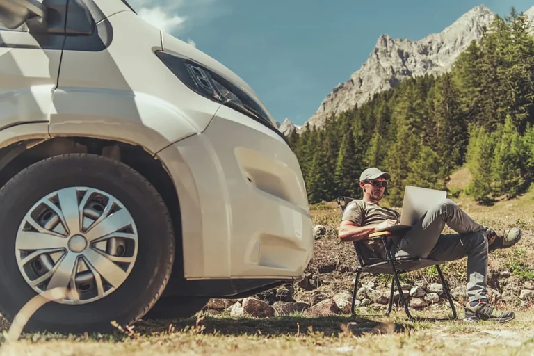 Many using laptop in nature next to an RV